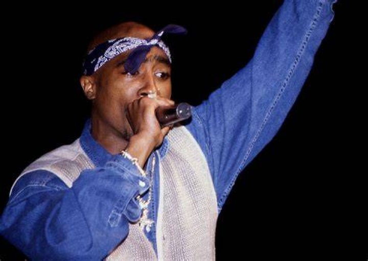 Tupac Shakur with a microphone on stage Tupac Shakur with a microphone on stage